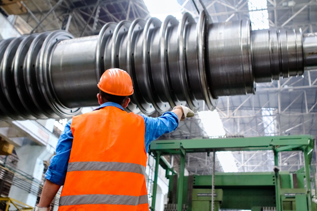 Worker in a hard hat and high-visibility vest in an industrial shop